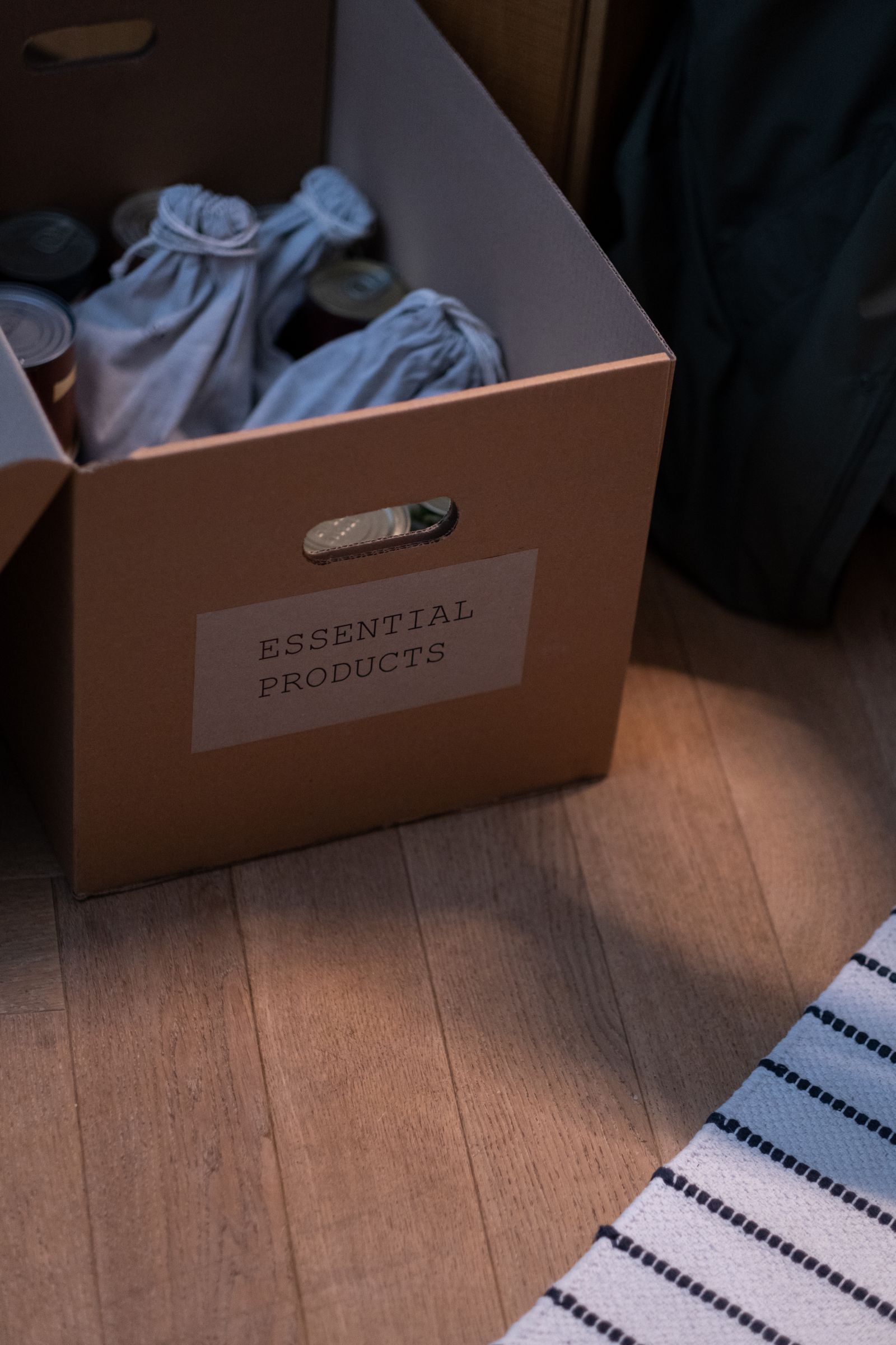 An open box labelled Essential Products, filled with cloth bags and supplies