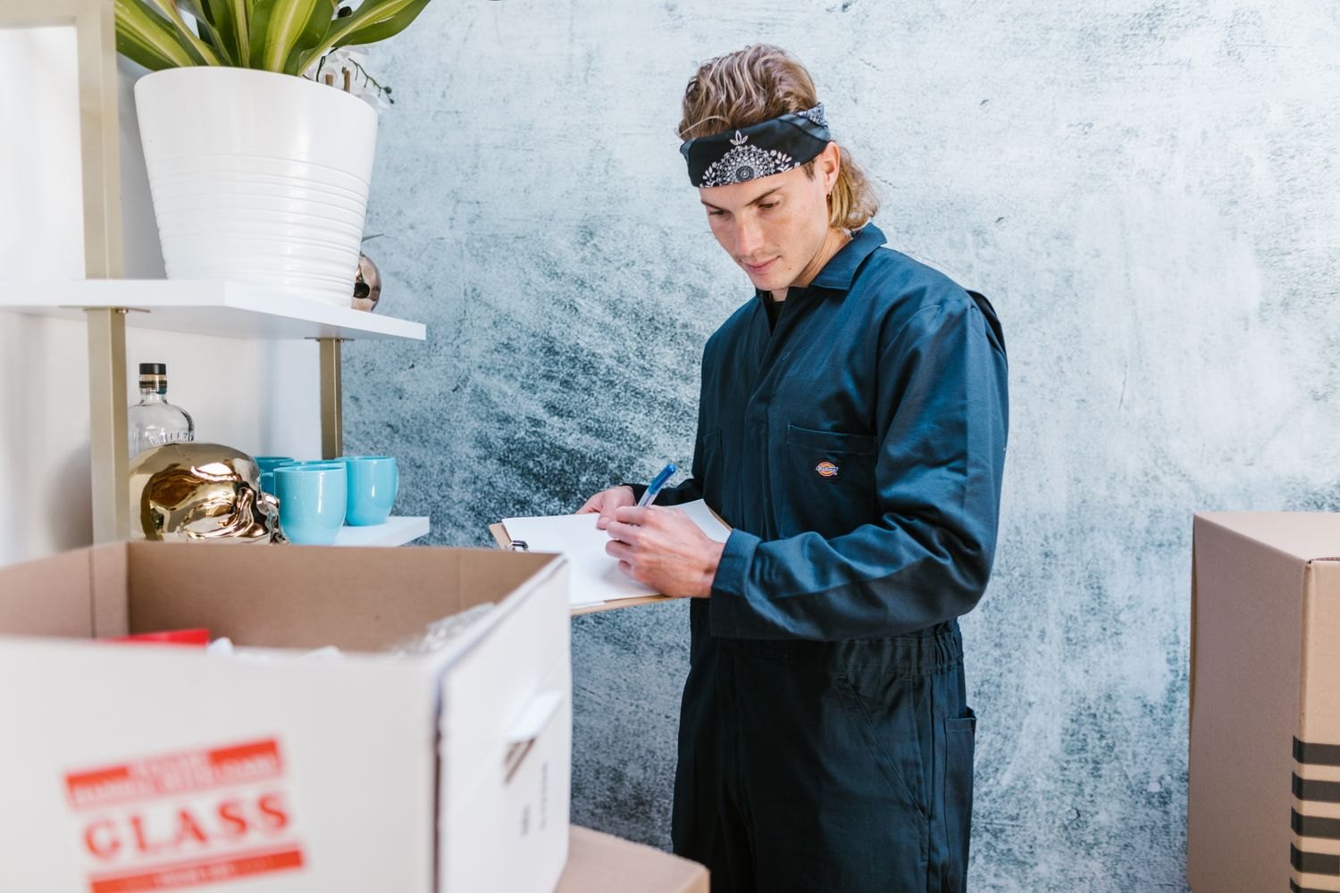 A man recording items beside boxes and a shelf