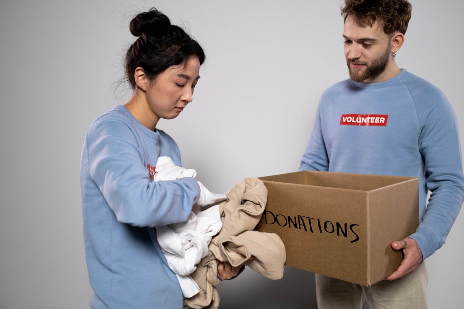 Two people sorting clothes into a donation box