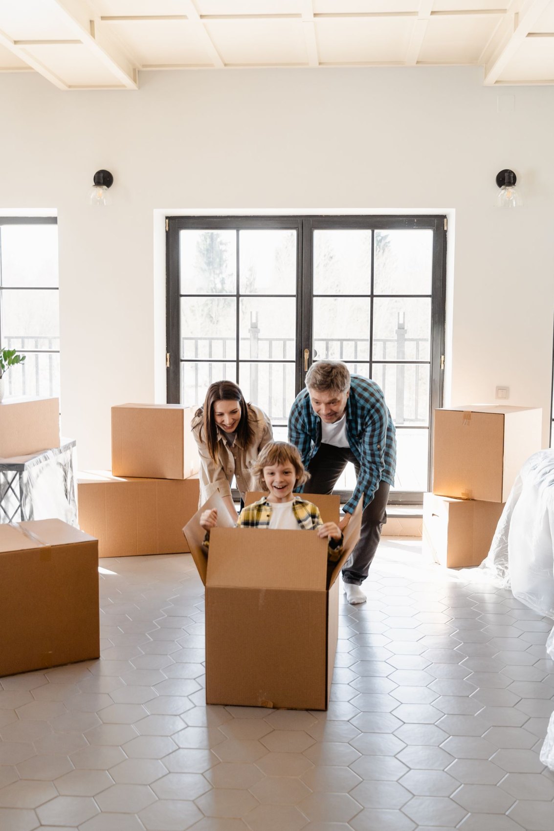 A family with a child playing among moving boxes