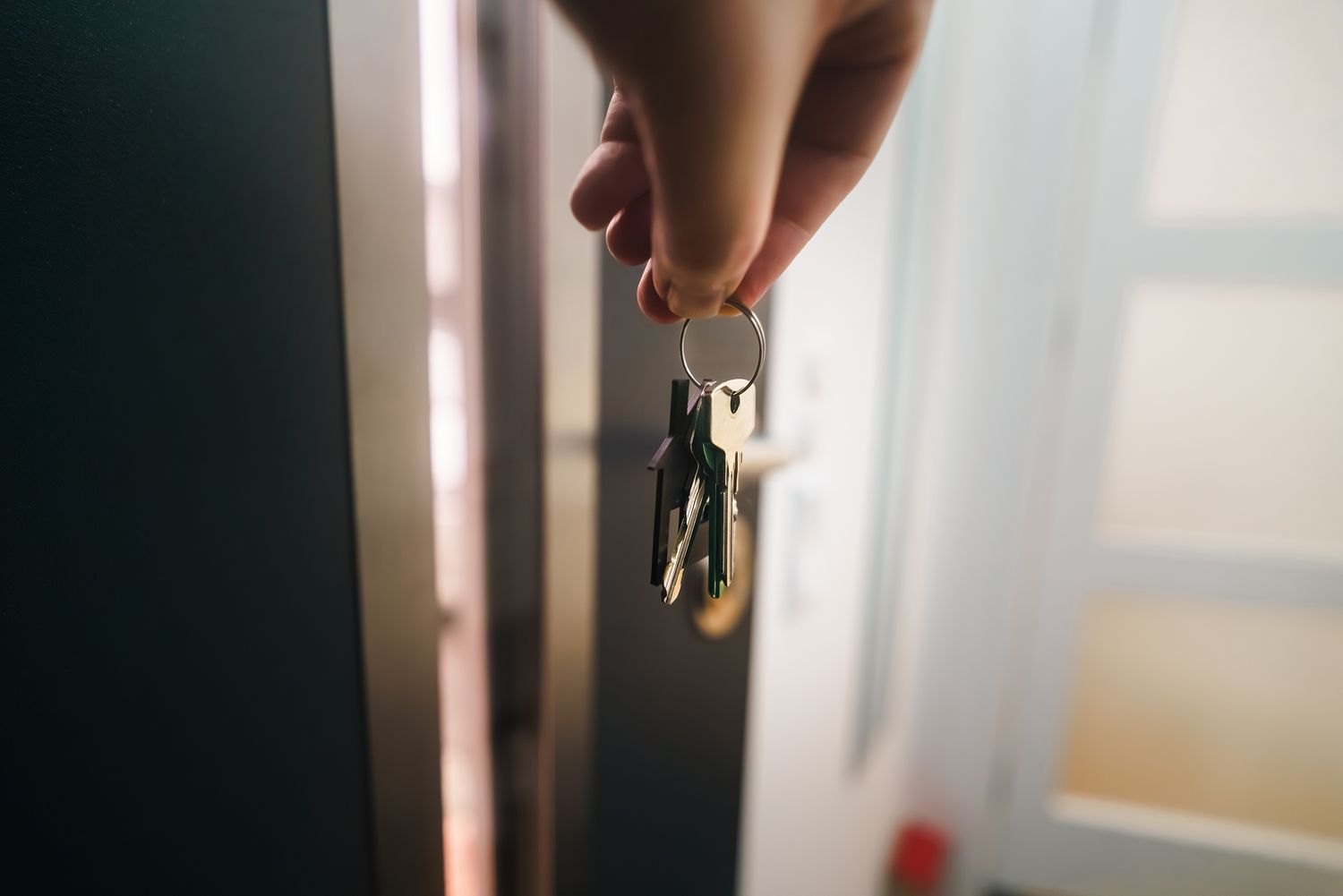 A hand holding house keys by a door