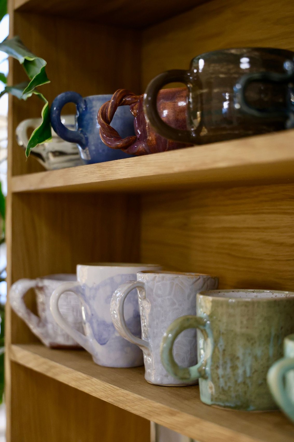 Ceramic mugs with handles on a wooden shelf