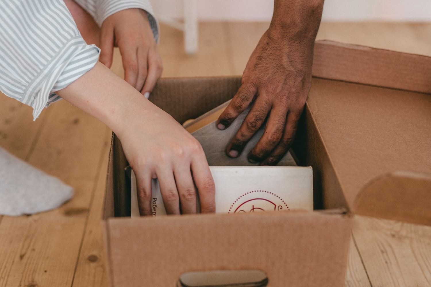 Hands placing books into a cardboard box