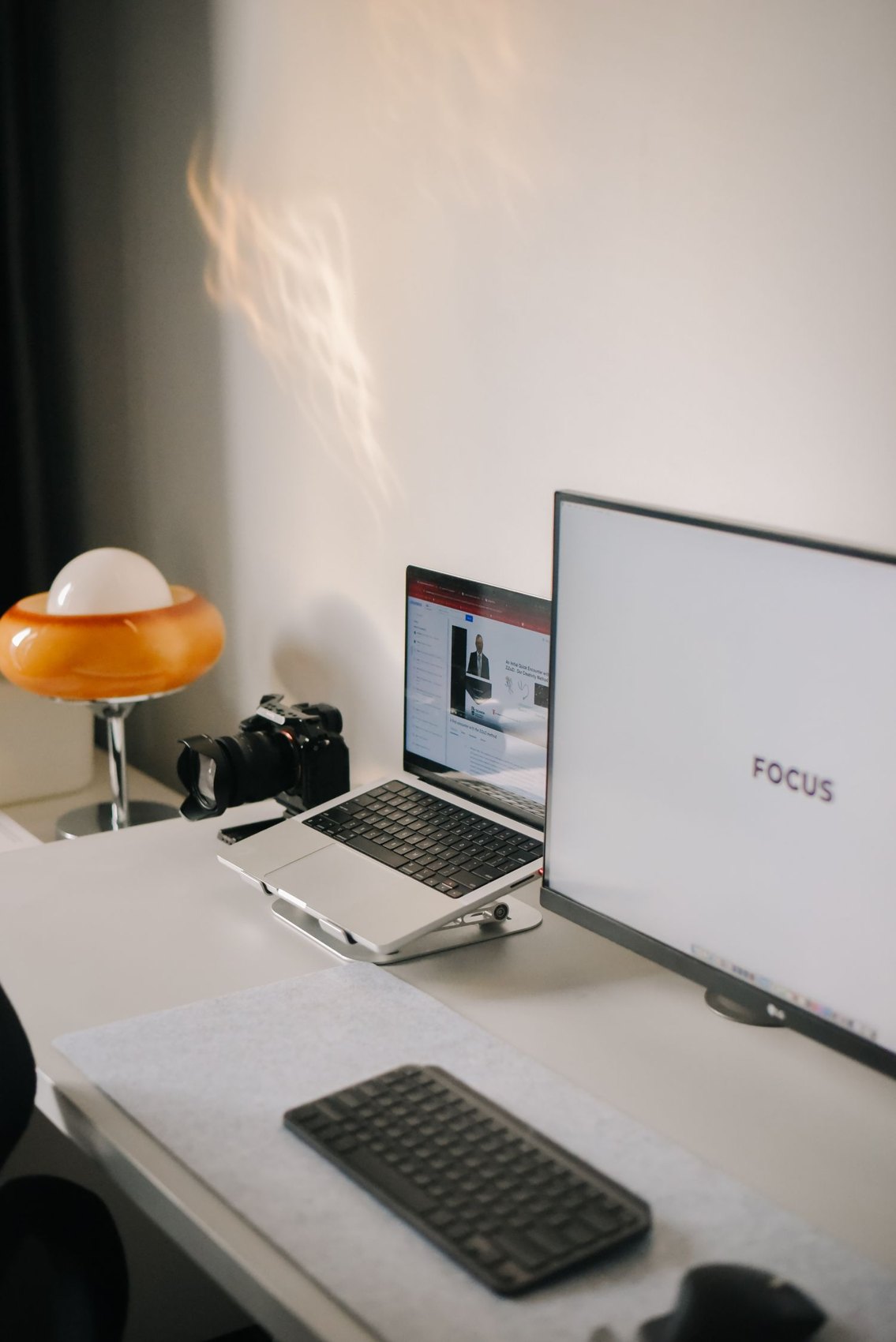 A monitor beside a laptop and keyboard on a desk