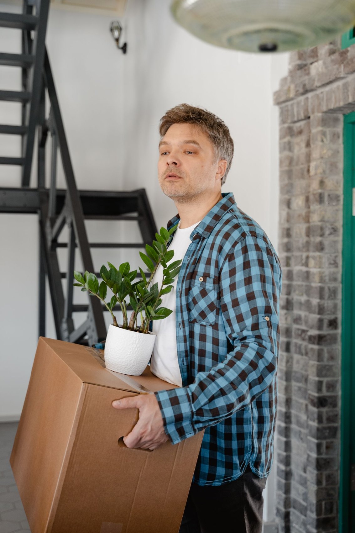 A man carrying a houseplant and a box