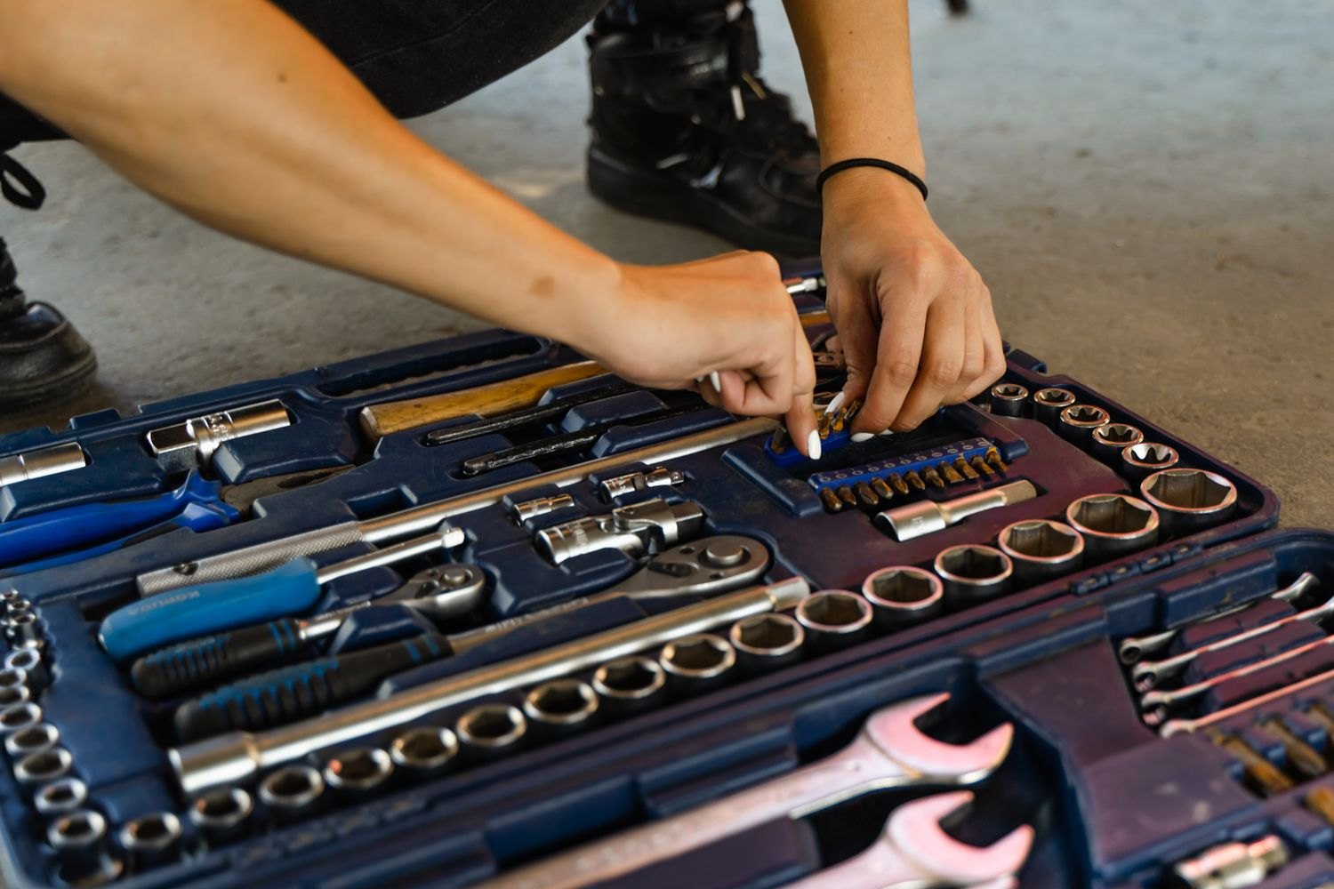 Hands choosing a tool from an open toolbox