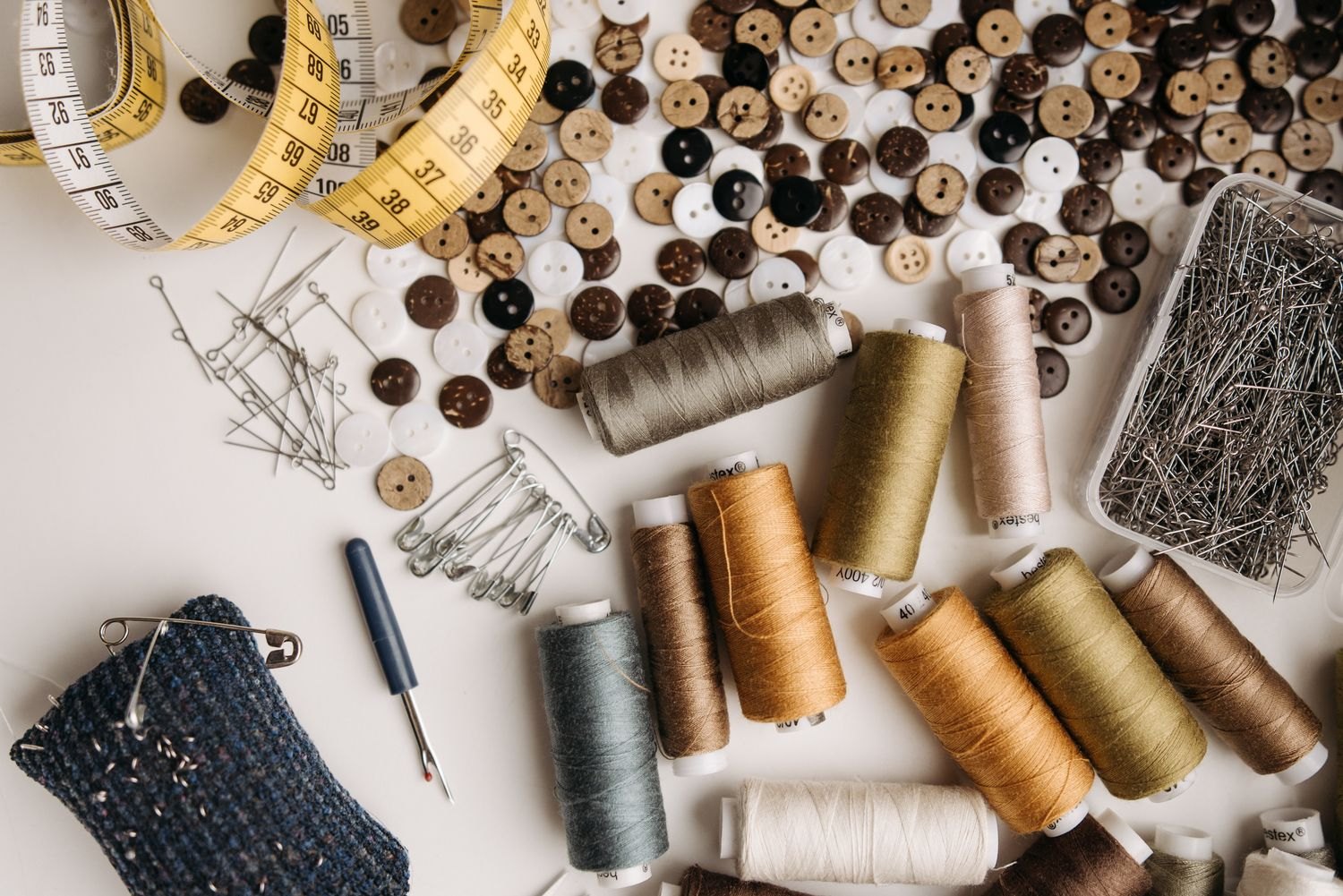 Sewing thread, buttons and a measuring tape on fabric