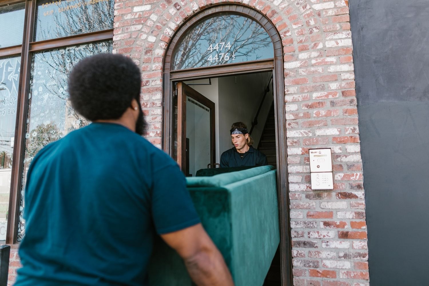 Two men carrying a sofa through a doorway