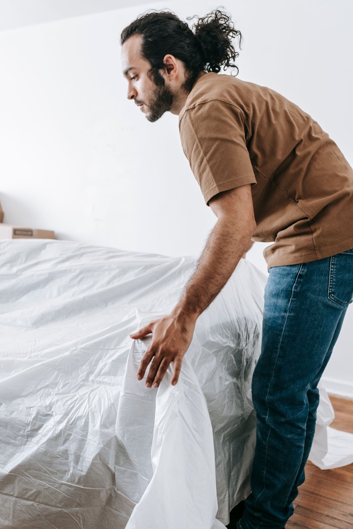 A man placing a protective cover over a sofa