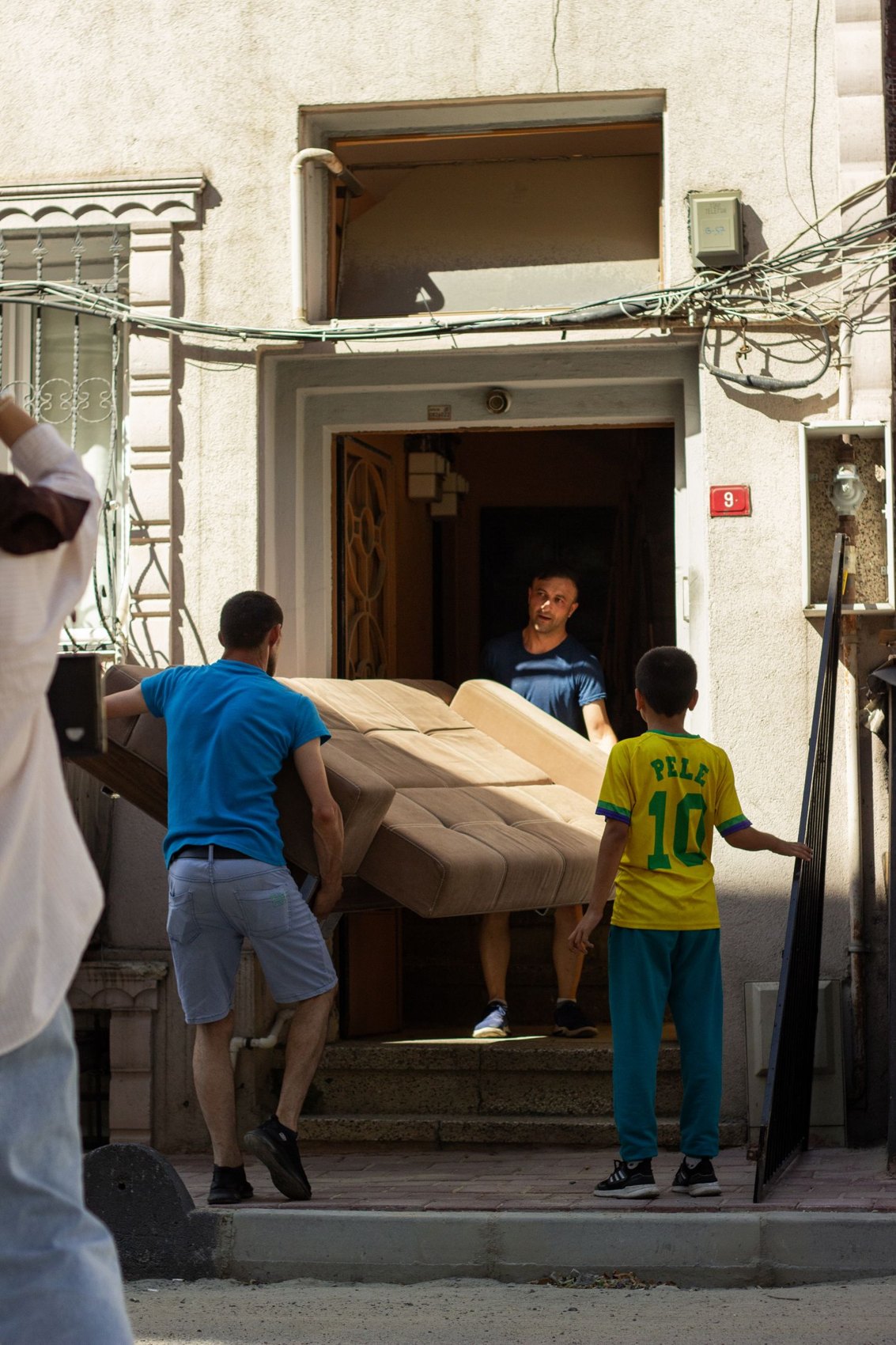 Several men moving a large piece of furniture through a doorway
