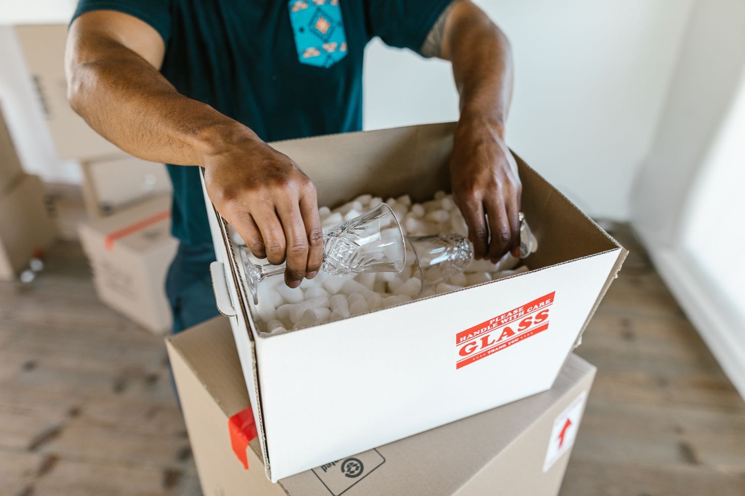 Glassware being cushioned with loose fill inside a box