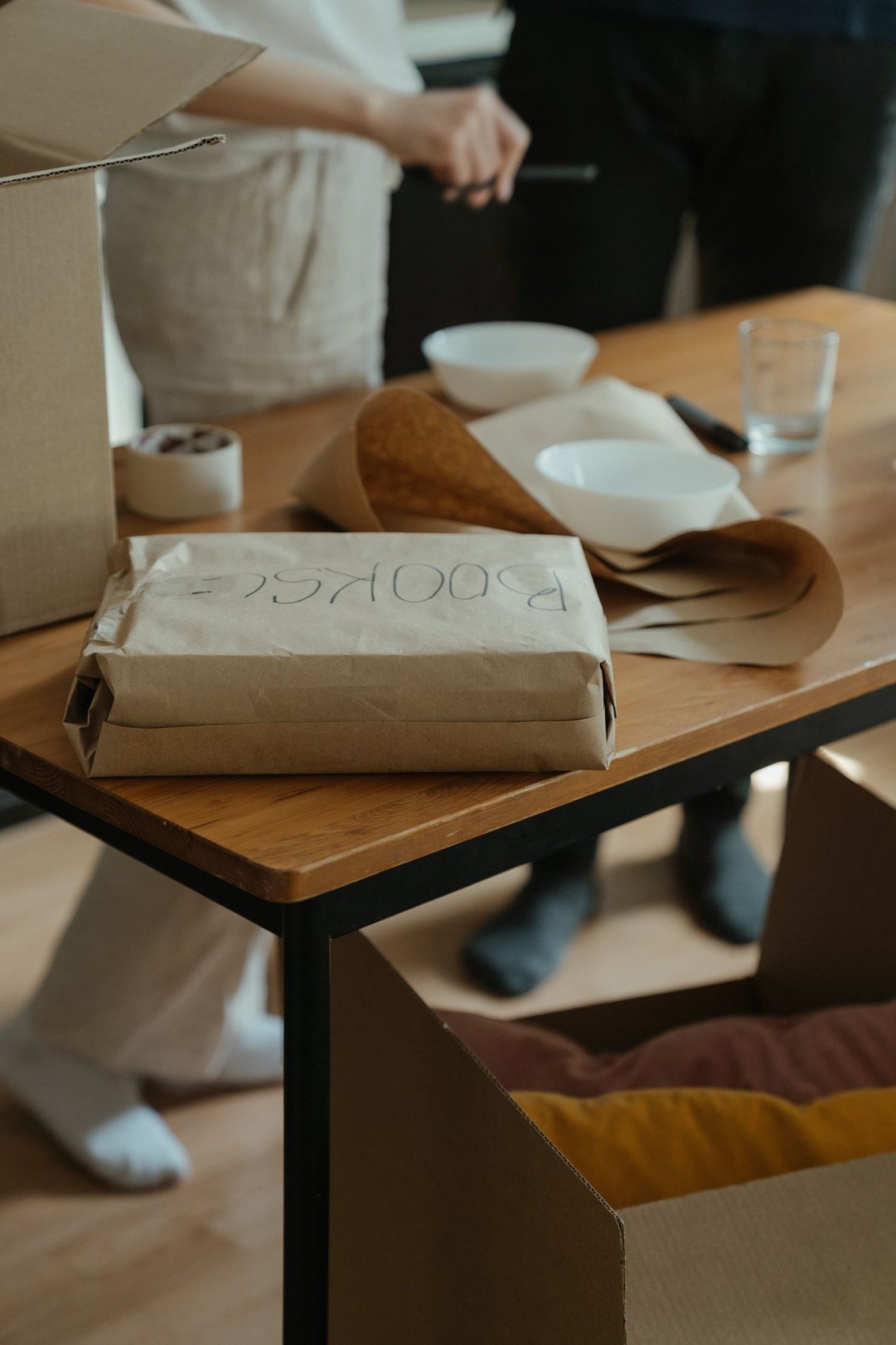 Packing paper and dishes on a work table beside boxes