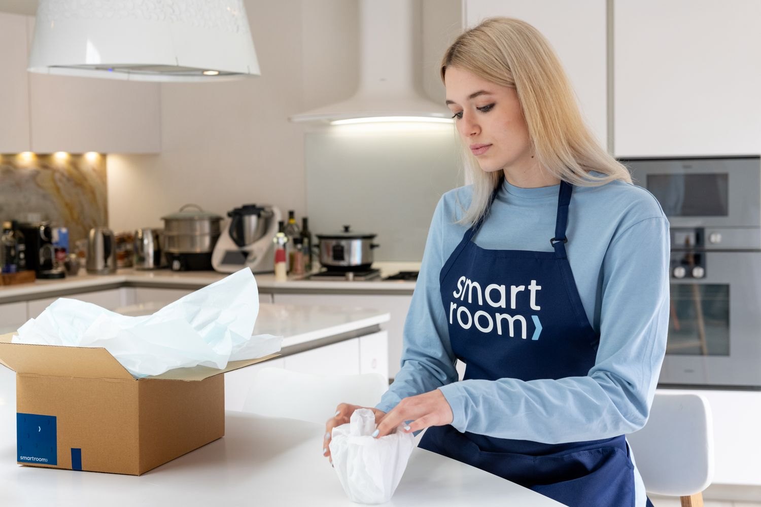 A woman unpacking a box at a kitchen worktop