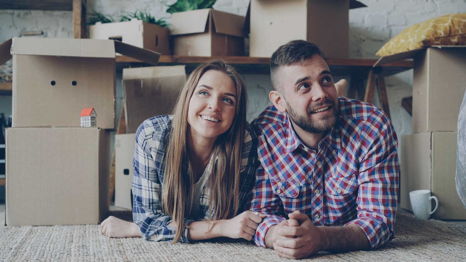 A couple resting in front of packed boxes in a new home