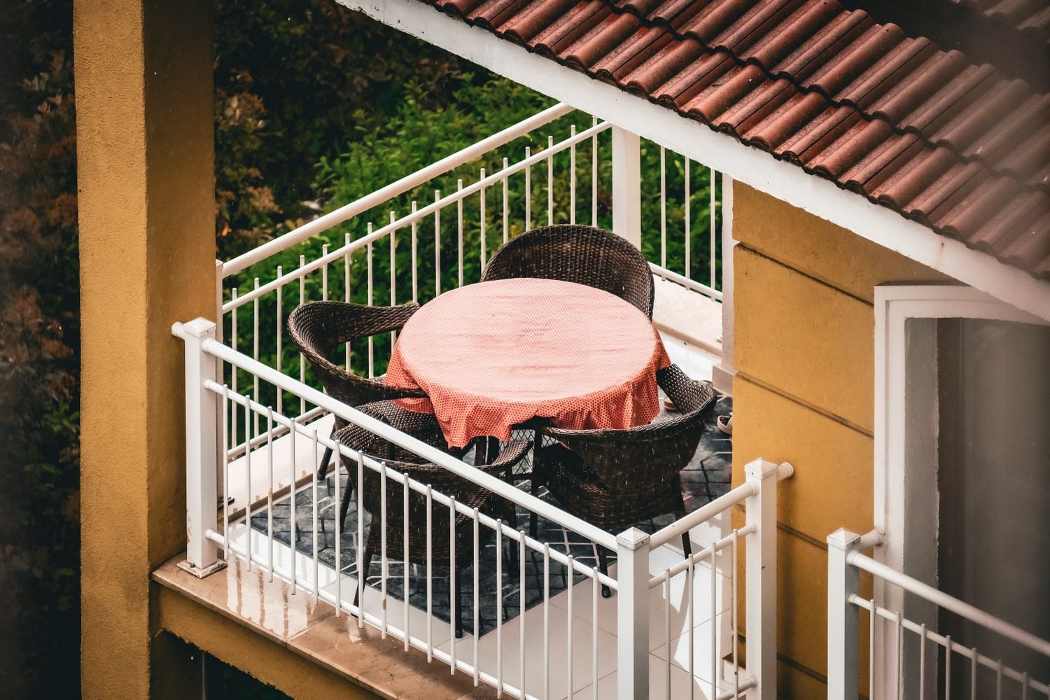 A small balcony with a table and chairs in wet weather